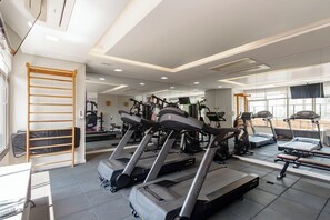 Ein Fitnessstudio mit Laufbändern, Crosstrainern und einer Gewichtbank.