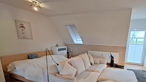 A modern living room with a sofa, a small table, and a radiator. - Ferienunterkunft in Dornumersiel (Dornum)