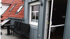 A balcony with a bench, a window, and a door leading to an interior space. - Ferienunterkunft in Dornumersiel (Dornum)