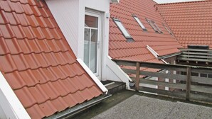 A residential building with red-tiled roofs, a white exterior, and a wooden fence. - Ferienunterkunft in Dornumersiel (Dornum)