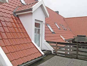 Ein Wohngebäude mit roten Ziegeldächern, einer weißen Fassade und einem Holzzaun.