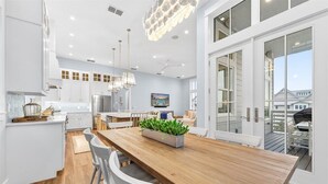 Een moderne keuken met witte kasten, een houten eiland en een eethoek met witte stoelen.