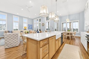 A spacious kitchen with a large island, wooden cabinets, and pendant lighting. - New 5 Bedroom Beach Home @Cinnamon Shore (Port Aransas)