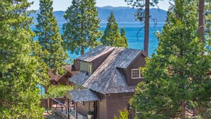 Une cabane avec une véranda, une cheminée en pierre et une vue sur le lac.
