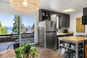 Eine moderne Küche mit einem Edelstahl-Kühlschrank, einem Holzespeisetisch und Meerblick.