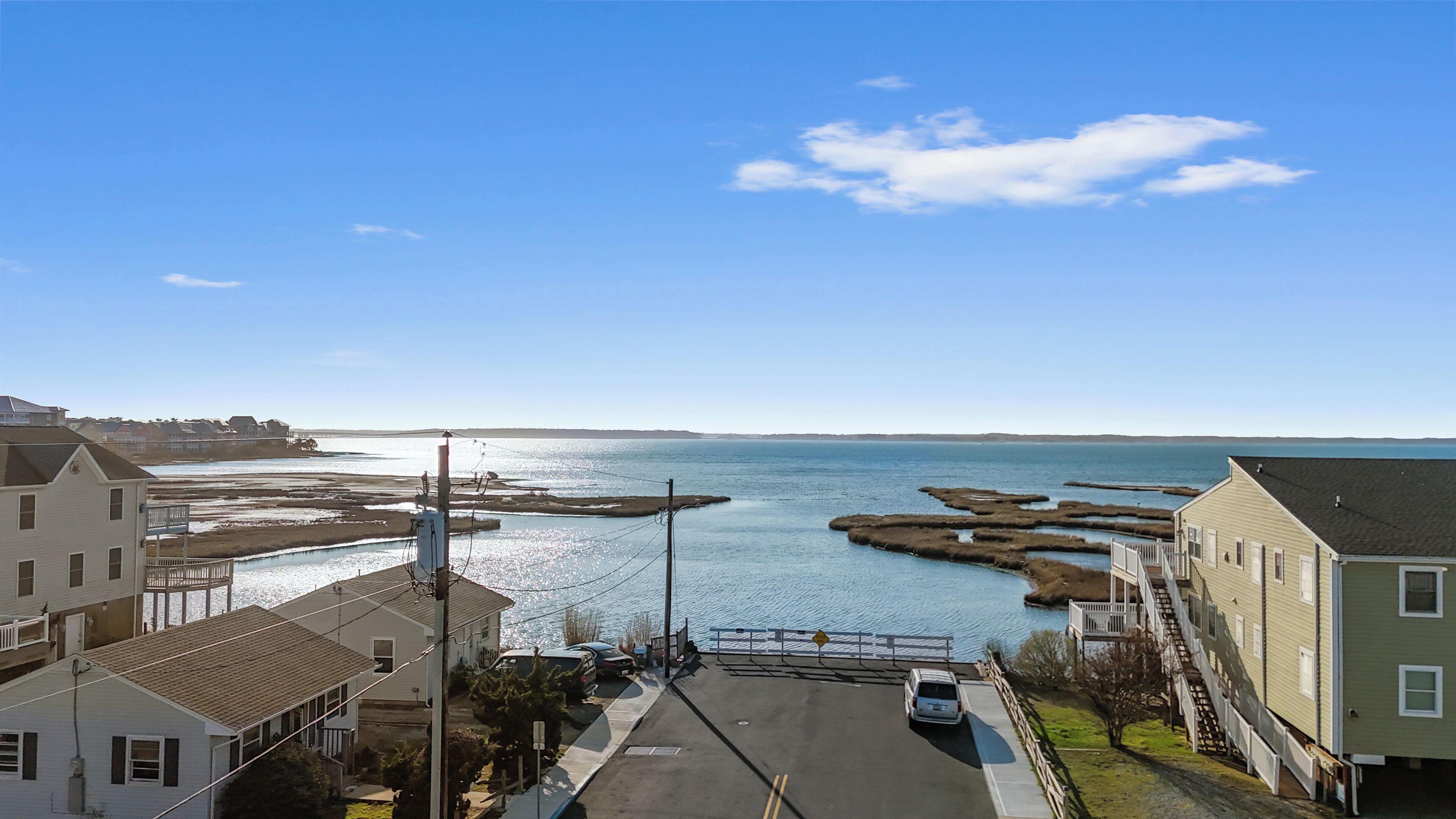 A coastal residential area with houses, a road, and a body of water.