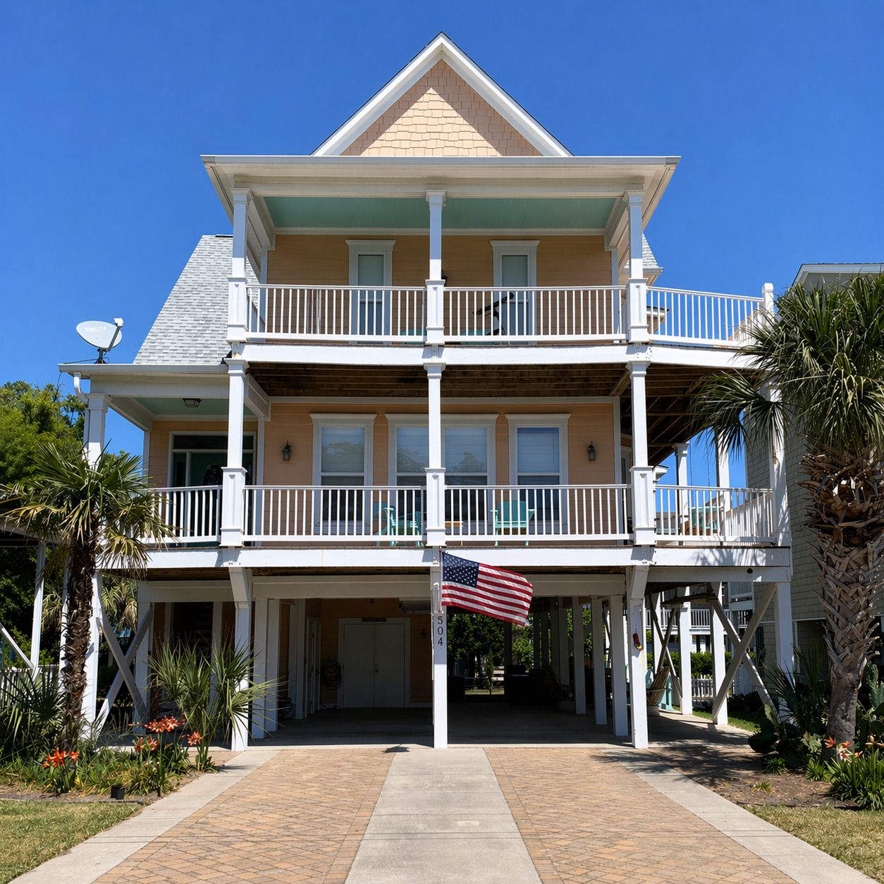 A two-story building with a balcony on the ground floor and a flagpole with an American flag.