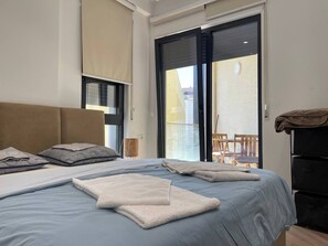 Ein Schlafzimmer mit Bett, Kopfstütze, Fenster und Balkon.
