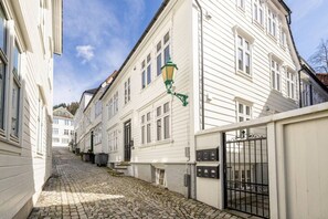 Eine Kopfsteinpflasterstraße mit weißen Gebäuden, einer grünen Straßenlaterne und einem verschlossenen Eingang.