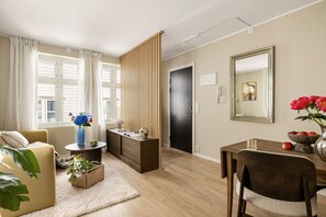 Ein modernes Wohnzimmer mit einer Couch, einem Esstisch, einem Beistelltisch mit einer Vase und einem großen Spiegel.