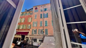 Een open balkon met uitzicht op een gebouw met meerdere ramen en een restaurant.
