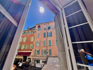 Een open balkon met uitzicht op een gebouw met meerdere ramen en een restaurant.