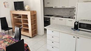 A compact kitchen with white cabinets, a microwave, a gas stove, and a small sink. - The villa is located 250 meters from the sandy beaches with crystal clear sea. (Baia Verde)