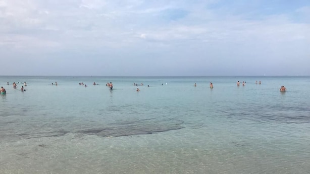 A beach with clear water and people swimming. - The villa is located 250 meters from the sandy beaches with crystal clear sea. (Baia Verde)