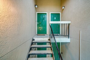 A staircase leading to two green doors with a white handrail and a wall-mounted light fixture.