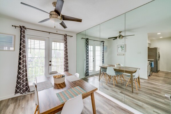 A dining area with a wooden table, chairs, and a ceiling fan.