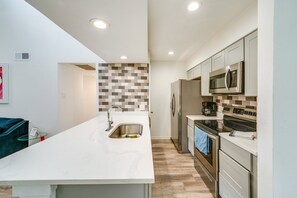 A modern kitchen with a white countertop, stainless steel appliances, and a herringbone-patterned backsplash.