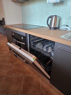 Una cucina con lavastoviglie, bollitore e schienale piastrellato.