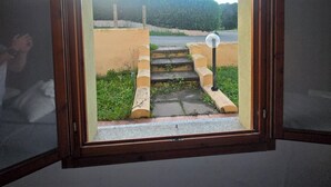 Ein Zimmer mit einem Fenster, das eine Außentreppe zu einem Tor zeigt.
