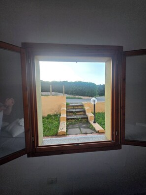 Ein Zimmer mit einem Fenster, das eine Außentreppe zu einem Tor zeigt.