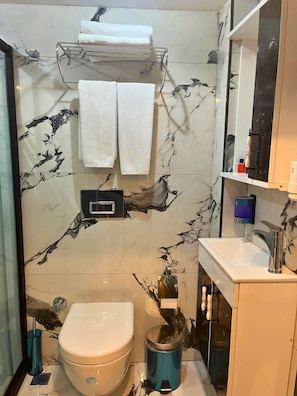 Uma casa de banho com sanita, lavatório e porta-toalhas.