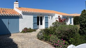 A white building with a tiled roof, a blue door, and a gravel driveway. - House with pets allowed - 4 guests (Barbâtre)