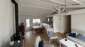 A spacious living area with a dining table, striped sofa, and a black stove. - House with pets allowed - 4 guests (Barbâtre)