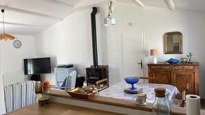 A cozy living room with a fireplace, a television, a dining table, and a kitchen area. - House with pets allowed - 4 guests (Barbâtre)