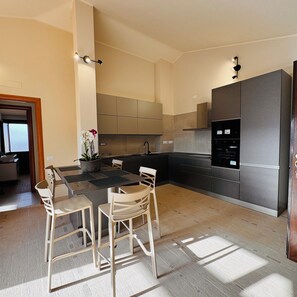 A modern kitchen with a dining area, featuring a central island, built-in appliances, and a view of the adjacent living space.