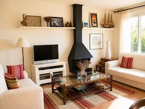 A living room with a fireplace, television, sofa, and decorative items on shelves. - Spacious house near La Fosca beach (Palamós)