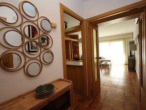 Un couloir avec une porte en bois, un mur recouvert de miroirs et un sol carrelé.
