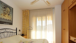 Un dormitorio con cama, armario, un cuadro y cortinas.