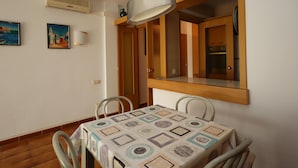Un comedor con una mesa, sillas, una lámpara de pared y un cuadro.