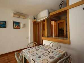 A dining area with a table, chairs, a wall-mounted lamp, and a painting. - Apartment with AC and pool - 4 guests (Lloret de Mar)