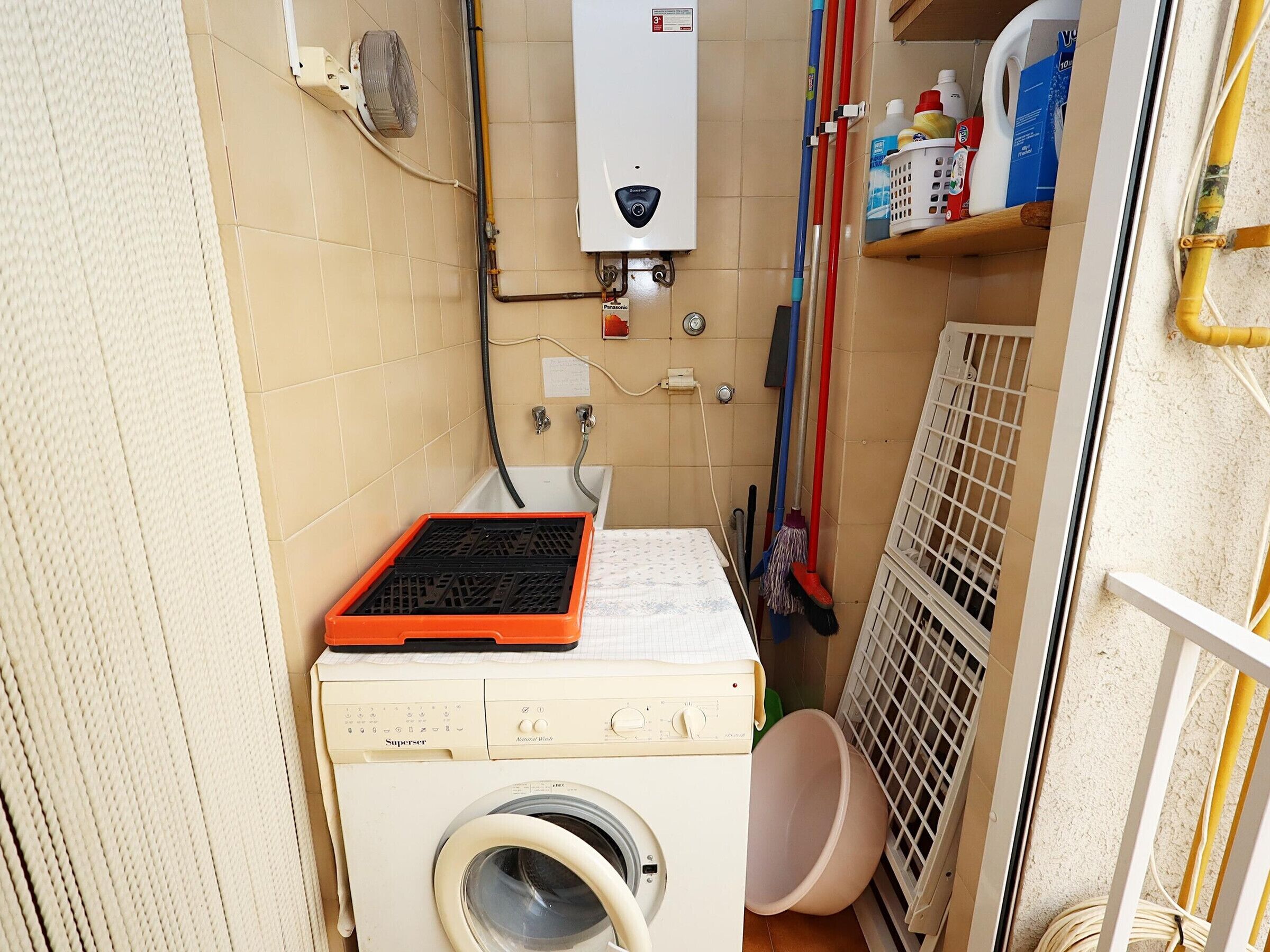 Une petite buanderie équipée d’un lave-linge, d’un radiateur et d’un étendoir.