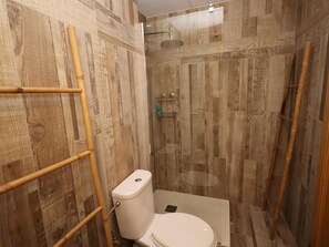 A bathroom with a toilet, shower, and wooden wall paneling. - Apartment with AC and pool - 4 guests (Lloret de Mar)