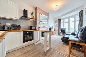 Eine moderne Küche mit weißen Schränken, einer Holz Arbeitsplatte und einem eingebauten Backofen.