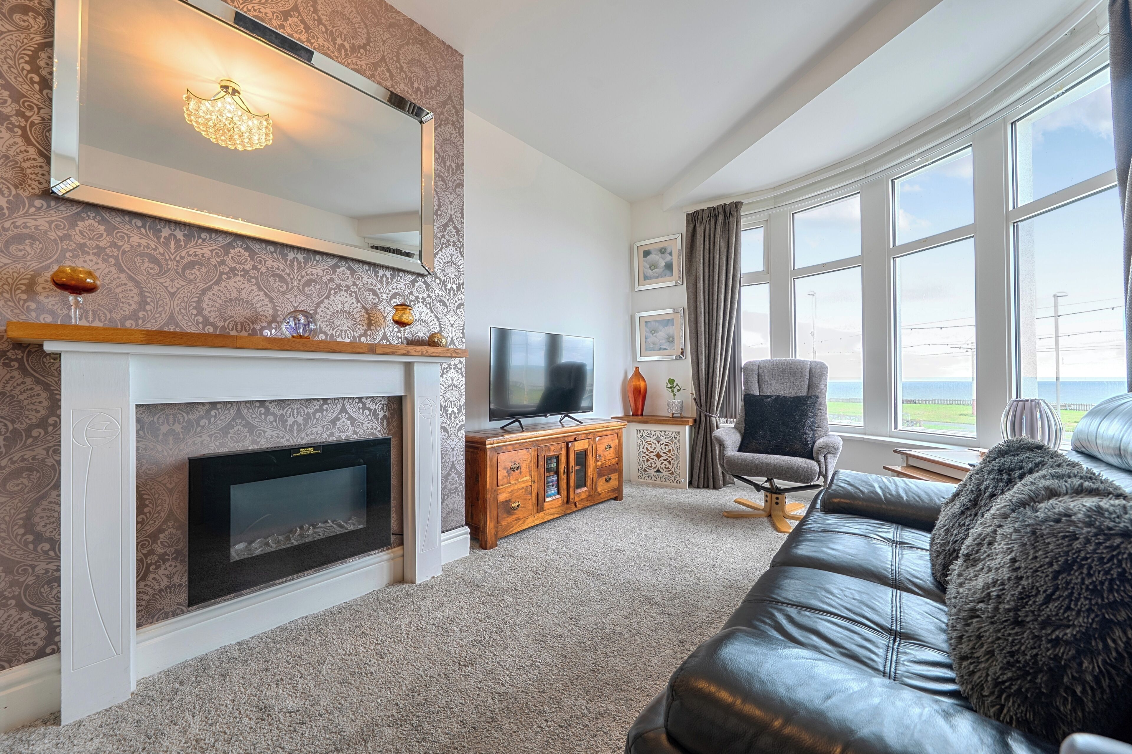 Una sala de estar con chimenea, televisión y vistas al exterior.
