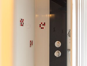 Une salle de bain avec un mur blanc, des carreaux rouges et blancs, et une porte noire.