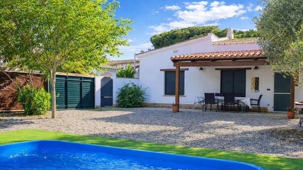 A swimming pool with a pergola, a patio with outdoor seating, and a white building with a tiled roof. - Charming house near beach - Costa Brava (Palamós)