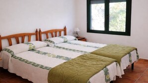 A double bed with a wooden headboard, a nightstand with a lamp, and a window with a view of trees. - Charming house near beach - Costa Brava (Palamós)