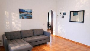 A living room with a grey sofa, a painting, and a mirror on the wall. - Charming house near beach - Costa Brava (Palamós)