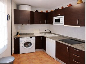 A compact kitchen with a washing machine, a microwave, and a sink. - Charming house near beach - Costa Brava (Palamós)