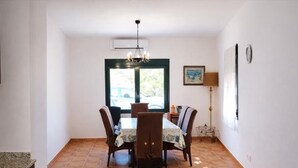A dining area with a table and chairs, a chandelier, a window, and a lamp. - Charming house near beach - Costa Brava (Palamós)