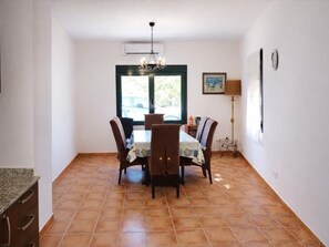 A dining area with a table and chairs, a chandelier, a window, and a lamp. - Charming house near beach - Costa Brava (Palamós)