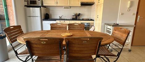 Una cocina con una mesa redonda de comedor, seis sillas y varios electrodomésticos.