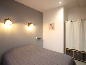 Ein Schlafzimmer mit einem Bett, zwei Wandleuchten, einem gerahmten Bild und einer Duschvorhang.