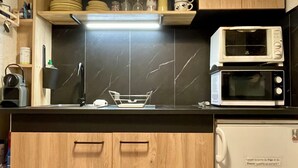 Eine Küche mit schwarzem Arbeitsplatz, zwei Mikrowellen, einem Wasserkocher und Holzschränken.