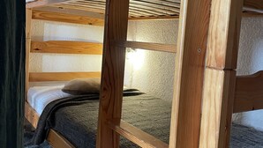 Ein Stockbett mit Holzrahmen und weißer Bettwäsche.