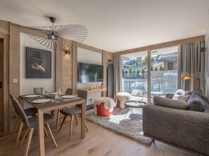 Ein modernes Wohnzimmer mit Essbereich, großen Fenstern und einem gemütlichen Kamin.